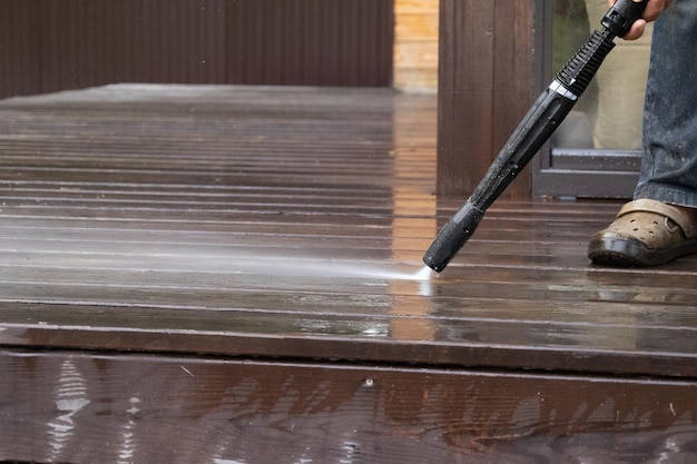 Man using pressure washer to clean a wood deck